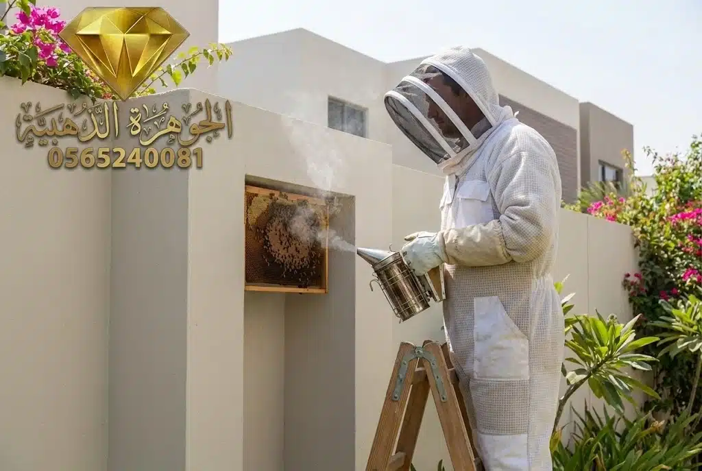 فني شركة الجوهرة الذهبية يرتدي بدلة حماية كاملة أثناء إزالة خلية نحل بأمان في فيلا بجدة باستخدام تقنية التدخين.